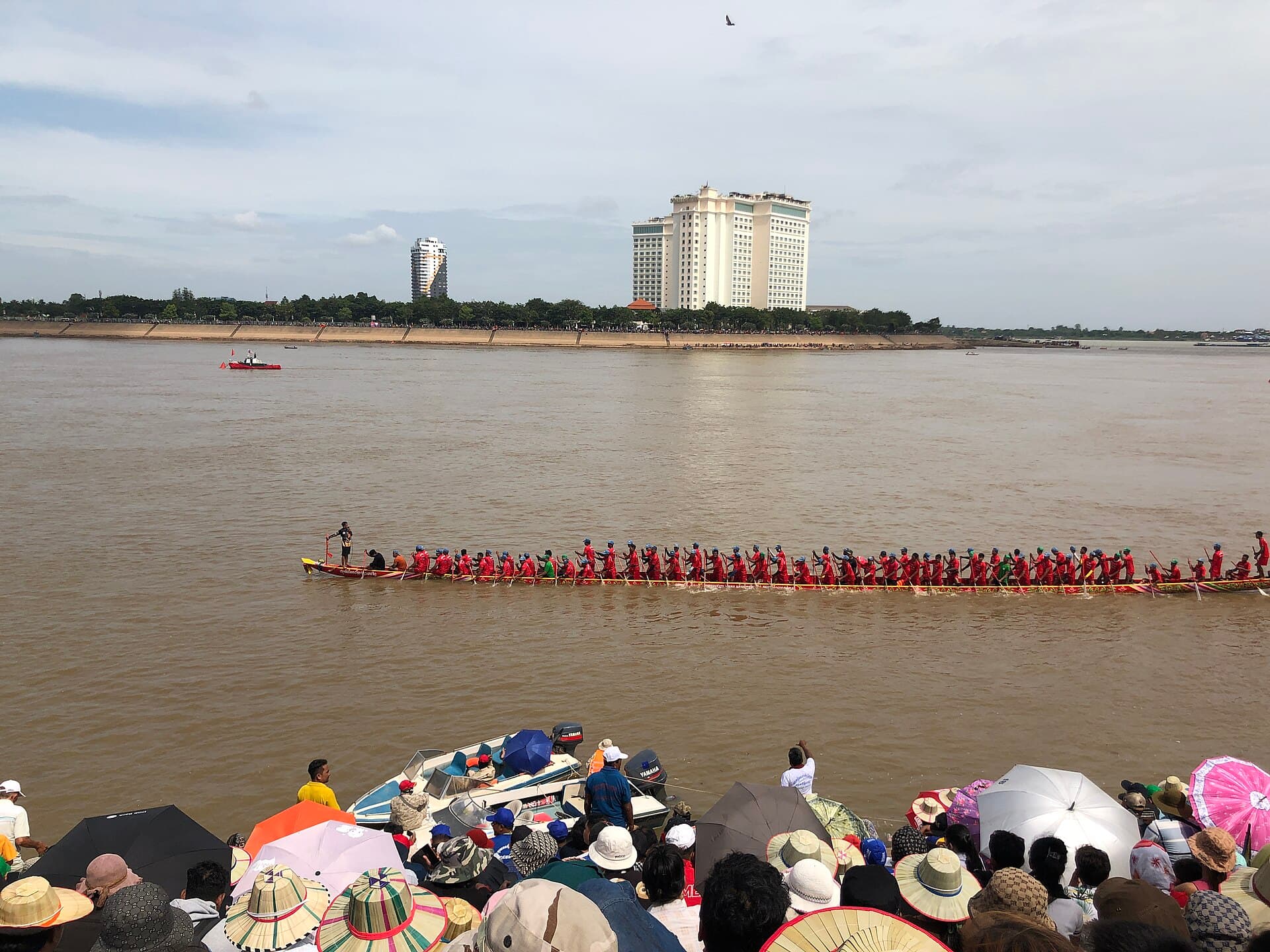A long boat race at the Water Festival in Phnom Penh, with spectators on the bank