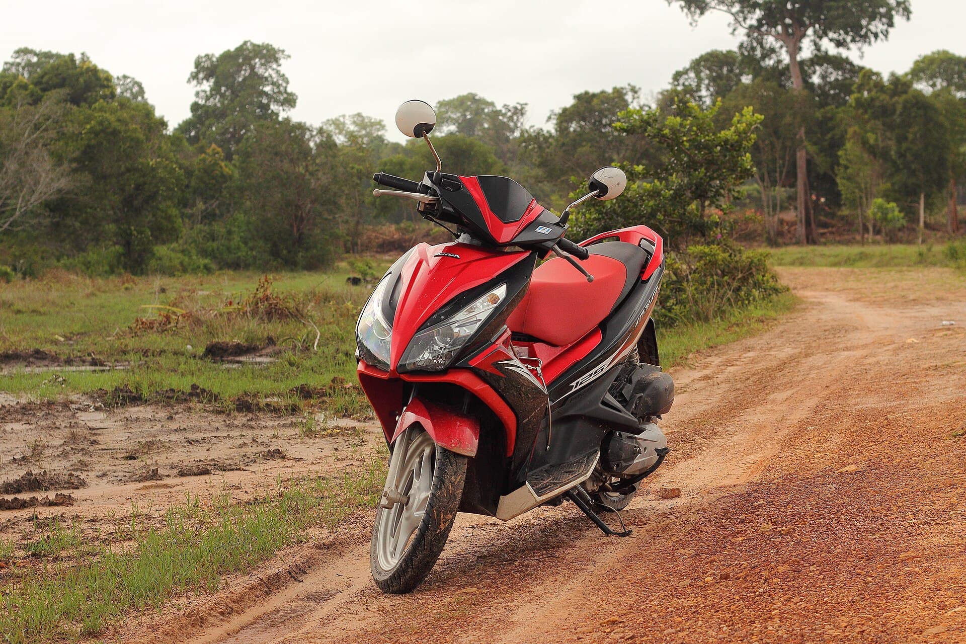 A red motorbike on a dirt road in Cambodia