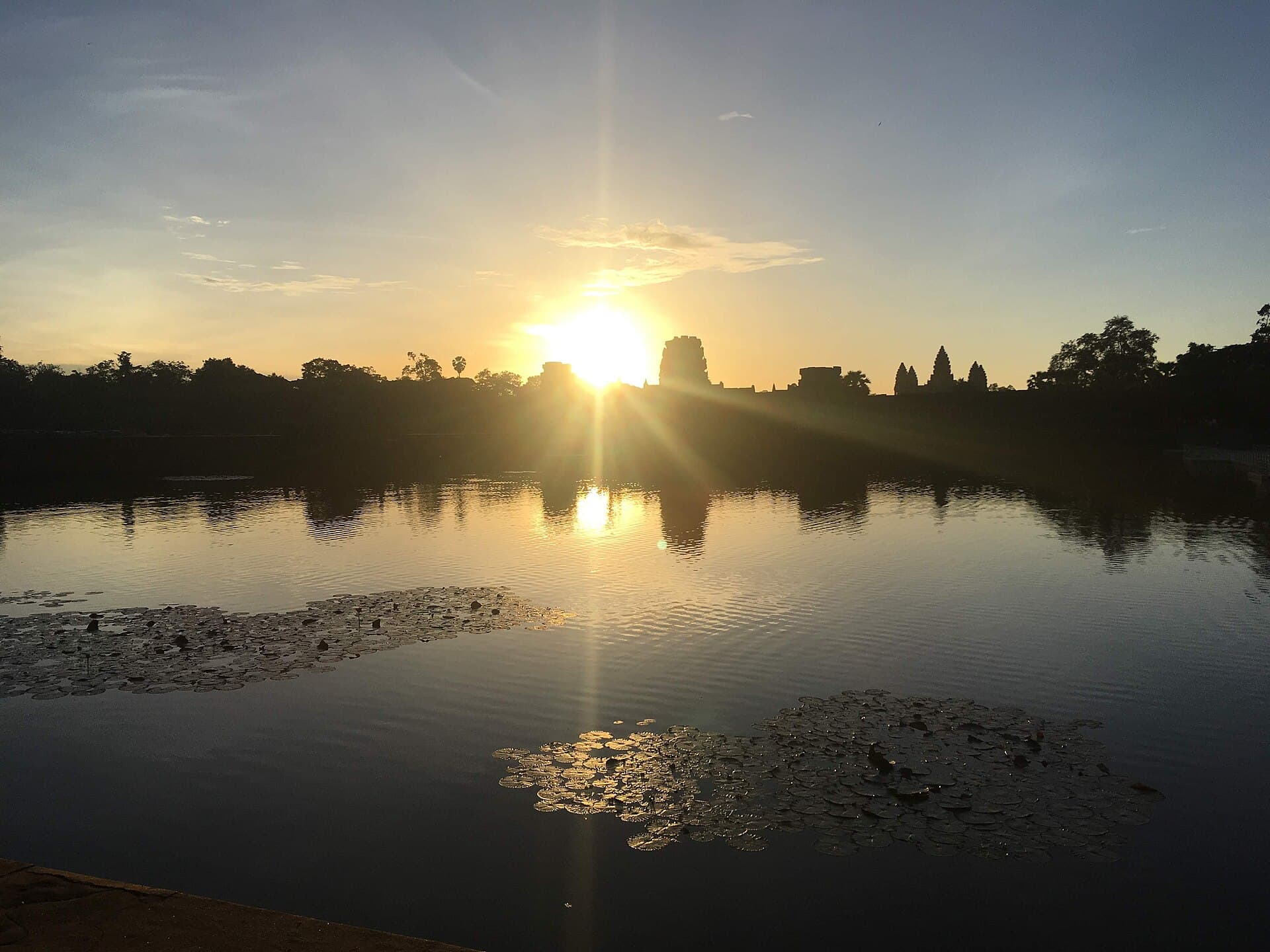 Sunrise over the moat of Angkor Wat, with water lilies and the temple towers in silhouette