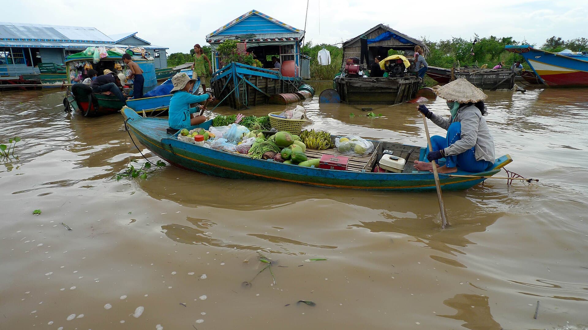 A boat of fruit and vegetables beside houseboats on Tonle Sap lake