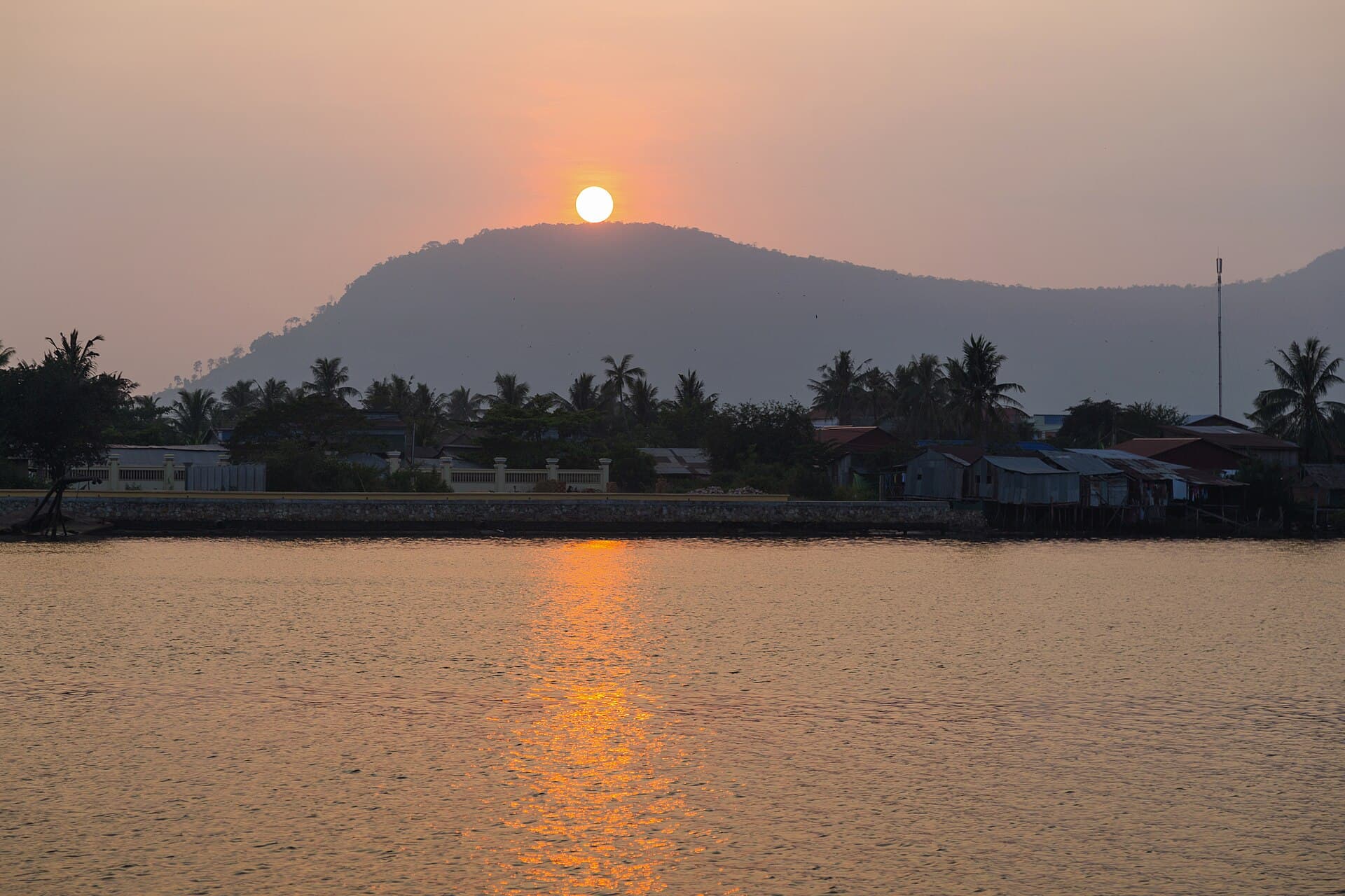 The sun setting behind a hill across the river at Kampot