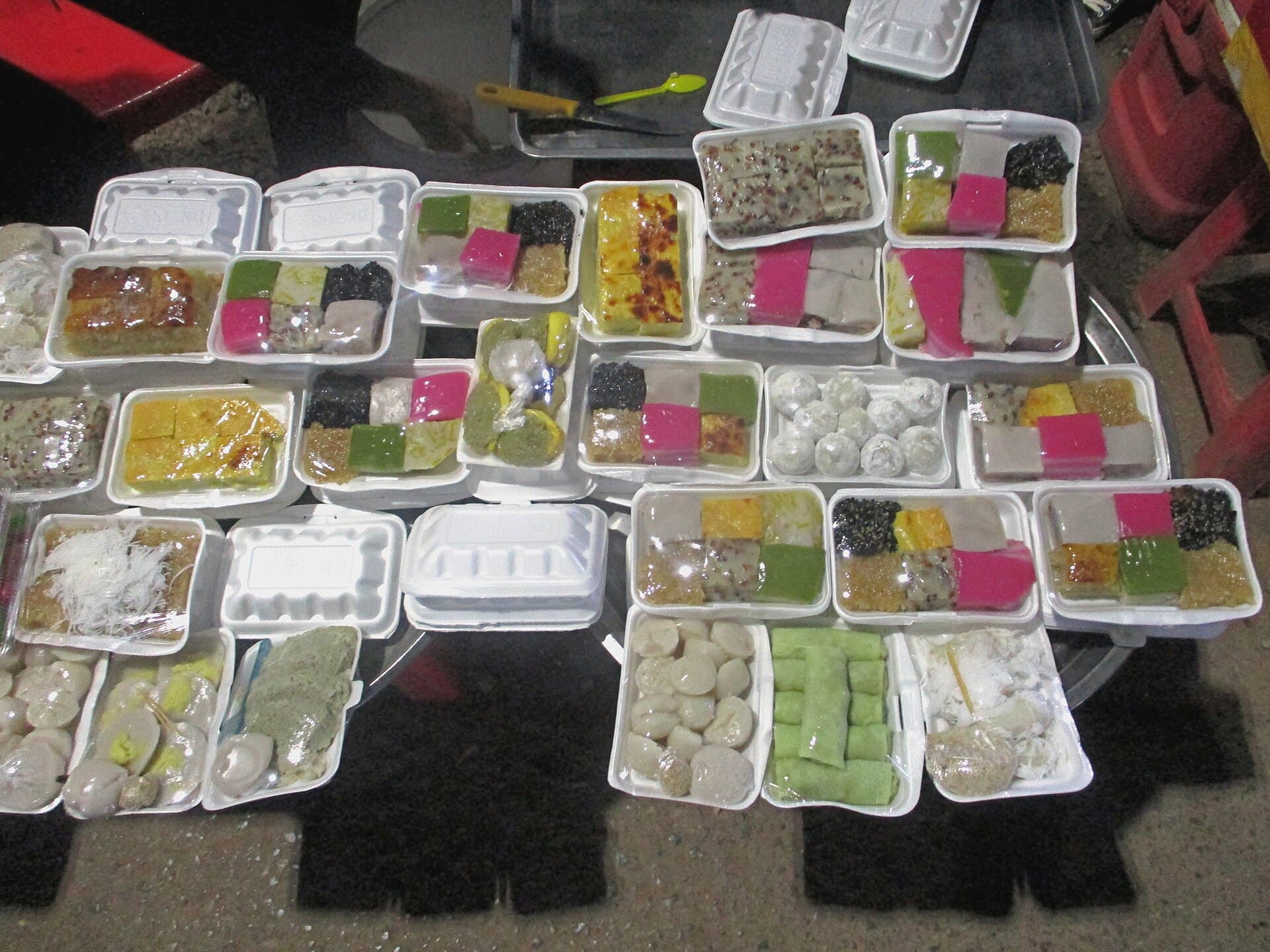 Overhead view of Cambodian sweets in white takeaway boxes